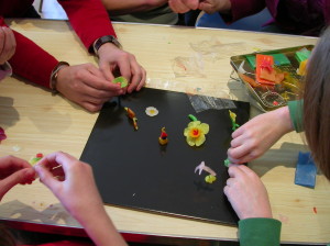Many hands working on beeswax sculptures
